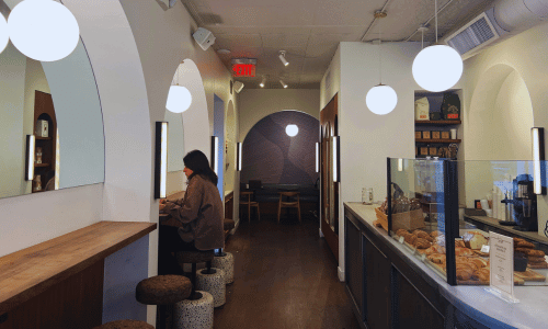 Hungry Ghost West Village | Minimalist Coffee in NYC Interior of Hungry Ghost coffee shop in West Village, New York City, showing a modern minimalist design with white arches, hanging lights, and a pastry counter.