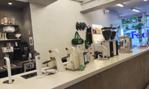 Do Not Feed the Alligators West Village | Espresso Bar 3 Interior of Do Not Feed Alligators café in the West Village featuring a sleek white counter, coffee equipment, minimalist décor, and a view toward the front window.