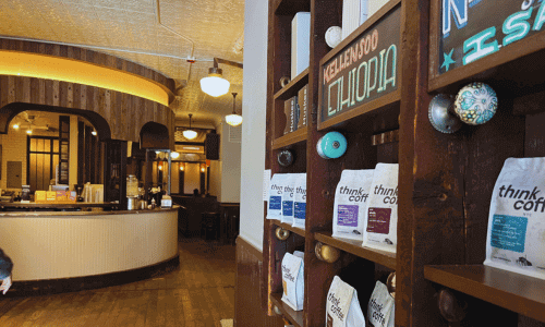 Think Coffee West Village – Fair-Trade Coffee Shop NYC 3 nterior of Think Coffee in the West Village showing shelves of coffee bags, warm wooden accents, curved counter, and soft ambient lighting.