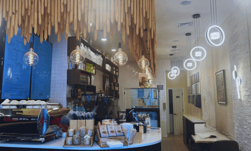 Inside Moka Mo Coffee House Greenwich Village interior with hanging lights, modern décor, and a marble counter displaying pastries and coffee items.