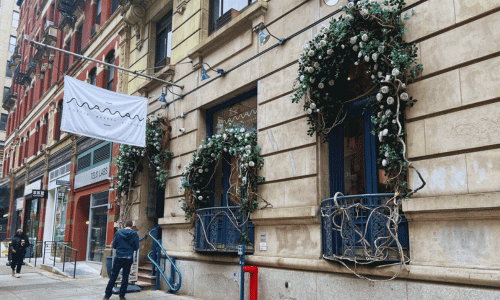 Maman Greenwich Village coffee shop exterior featuring floral window décor, elegant balconies, and a classic New York building façade along a quiet street.