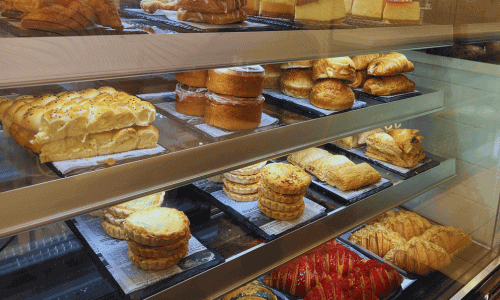 Pastries at Moka Mo Coffee House Greenwich Village displayed inside a well-lit bakery case filled with croissants, layered pastries, cakes, and assorted baked goods.