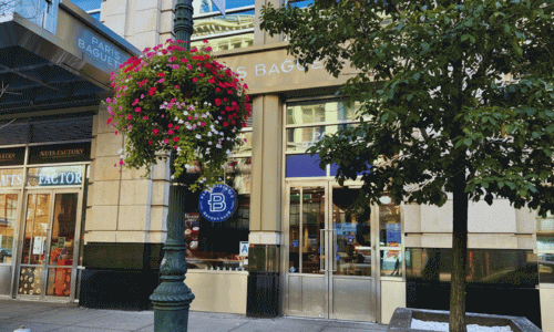 Exterior of Paris Baguette in Chelsea, Manhattan, with a bright storefront, floral street décor, and large glass entrance.