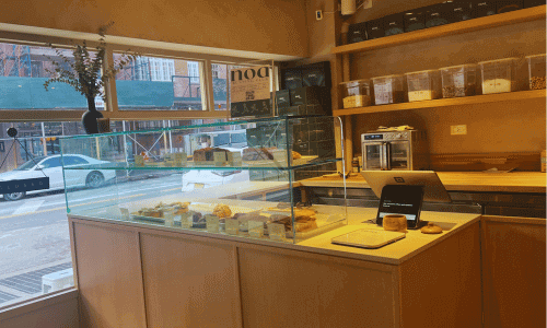 Interior of Noa a Café West Village with a glass pastry display showcasing baked goods in the West Village, Manhattan.