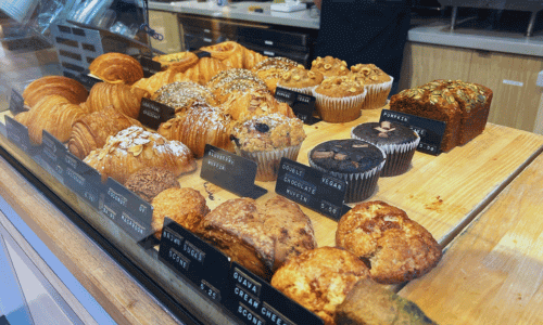 Pastries and muffins displayed behind glass at Kona Coffee Roasters Chelsea.