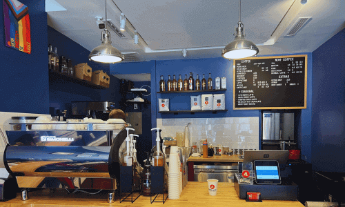 Absolute Coffee West Village – Best Coffee in NYC 4 Espresso machine and menu board behind the counter at Absolute Coffee West Village in Manhattan.