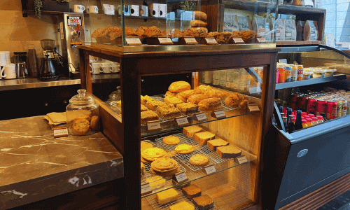 Glass pastry display filled with croissants, muffins, cookies, and baked goods inside Think Coffee near Hudson Yards in Chelsea.