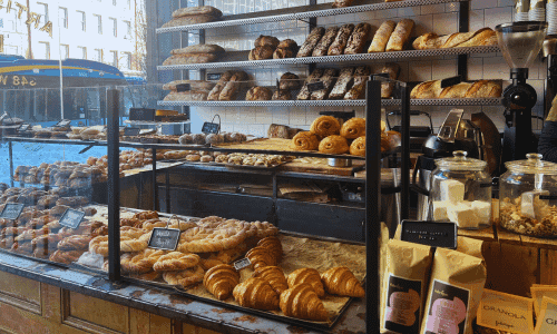Fabrique West Village – Best Swedish Bakery and Coffee NYC 3 Bakery display of bread and pastries with street view from inside Fabrique West Village coffee shop in NYC