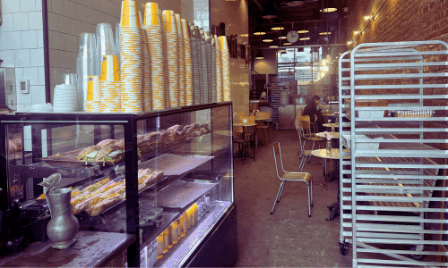 Fabrique West Village – Best Swedish Bakery and Coffee NYC 2 Interior of Fabrique West Village coffee shop in NYC with pastry display case and stacked coffee cups