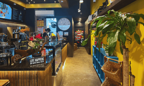 interior de Cafe By The Girls Chelsea NYC con barra de espresso asientos y plantas en 23rd Street